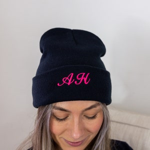 Op de afbeelding: Zwarte beanie met een roze geborduurde "AH" op de voorkant.