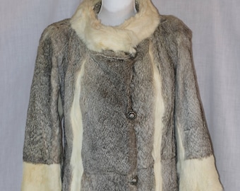 May include: A gray and white fur coat with a collar and cuffs made of white fur. The coat has a button closure and is lined with a white fabric.