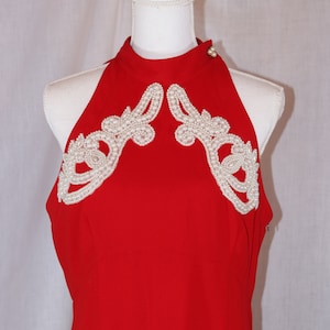 May include: A red halter dress with a high neckline and white pearl embellishments on the shoulders.
