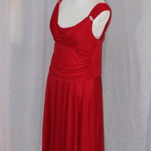 May include: A red sleeveless dress with a cowl neck and a flowing skirt. The dress has a fitted bodice and a gathered skirt. The dress is decorated with small rhinestones on the straps.