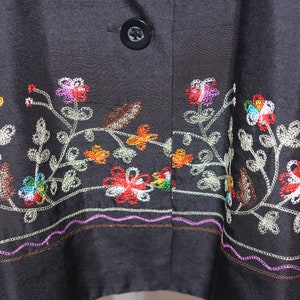 May include: Black silk jacket with colorful floral embroidery around the hem. The embroidery features a variety of flowers and leaves in shades of red, orange, yellow, green, blue, and white.