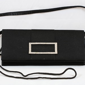 May include: A black satin clutch bag with a rhinestone-encrusted rectangular clasp.