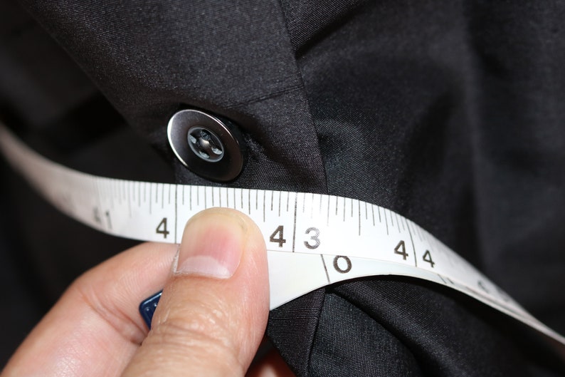 May include: A white measuring tape is wrapped around a black fabric shirt, with the numbers 4, 3, 0, and 4 visible.
