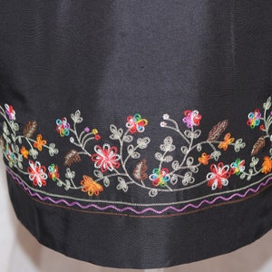 May include: Black jacket with a colorful floral embroidery design around the bottom hem.