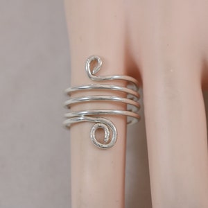 May include: Silver ring with a spiral design. The ring is made of multiple coils of wire that are twisted together.