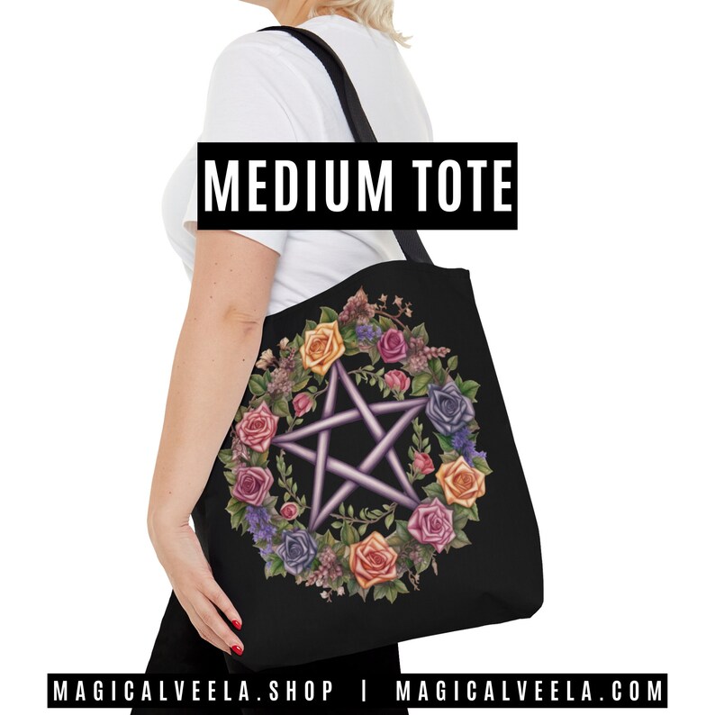 Puede incluir: Bolsa de tela negra con un pentagrama rodeado de una corona de rosas de colores. La bolsa tiene el texto "MEDIUM TOTE" impreso en ella.