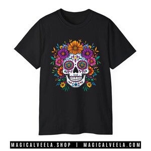 May include: Black t-shirt with a white sugar skull design surrounded by colorful flowers. The skull has pink and purple eyes and a pink tongue.