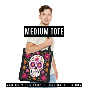 May include: Black medium tote bag featuring a colorful sugar skull design with pink, orange, and yellow floral accents. The tote bag has a black handle and the text "MEDIUM TOTE" in a black rectangle.