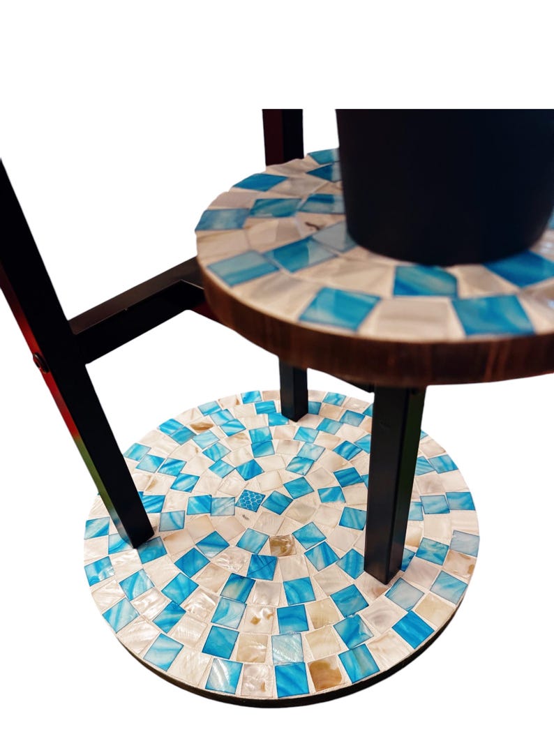 May include: A three-tiered plant stand with a black metal frame and round, mosaic-tiled shelves. The shelves are made of wood and have a blue and white mosaic pattern.