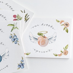May include: Four watercolor cards with the text "our little" and a different fruit on each card. The fruits are a blueberry, an apricot, a raspberry, and a peach. Each fruit has a halo and wings.