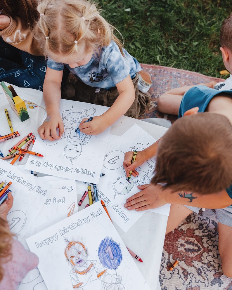 K&ouml;nnte beinhalten: Drei Kinder f&auml;rben personalisierte Geburtstagskarten mit Buntstiften aus. Die Karten zeigen eine Comiczeichnung eines Kindes mit einem Ballon und dem Text "happy birthday ila!"