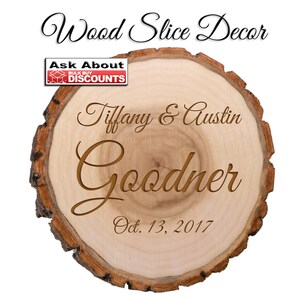 May include: A round wood slice with a light brown center and a dark brown bark edge. The text "Wood Slice Decor" is at the top. The names "Tiffany & Austin Goodner" and the date "Oct. 13, 2017" are engraved on the wood.