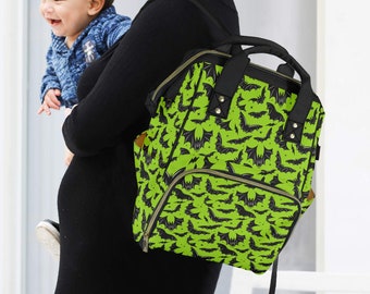 May include: A green and black backpack featuring a bat design. The bag has a top handle, a front pocket, and adjustable straps. The backpack is being carried over the shoulder.