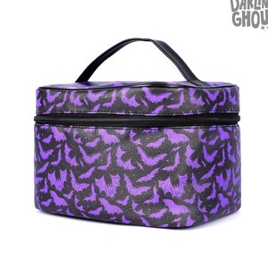 May include: Purple travel makeup bag with a black zipper and a black bat pattern. The bag has a black handle.