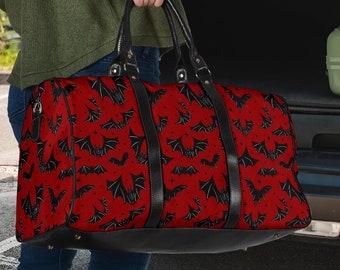 May include: A red and black travel bag with a bat pattern. The bag is in the trunk of a car.