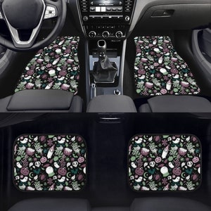 May include: Set of four black car floor mats with a Halloween-themed print. The print features ghosts, pumpkins, bats, spiders, and other spooky elements in shades of green, purple, and white on a black background.