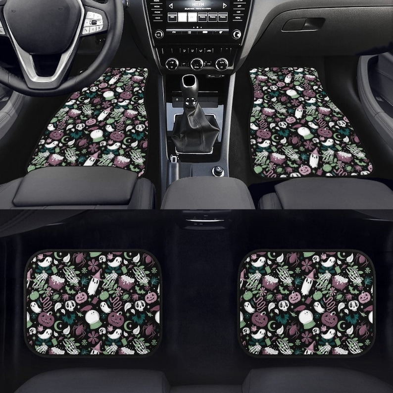 May include: Set of four black car floor mats with a Halloween-themed print. The print features ghosts, pumpkins, bats, spiders, and other spooky elements in shades of green, purple, and white on a black background.