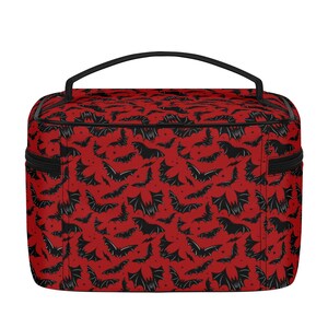 May include: Red and black travel makeup bag with a bat pattern. The bag has a black zipper and a black handle.