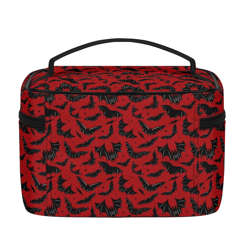 May include: Red and black travel makeup bag with a bat pattern. The bag has a black zipper and a black handle.