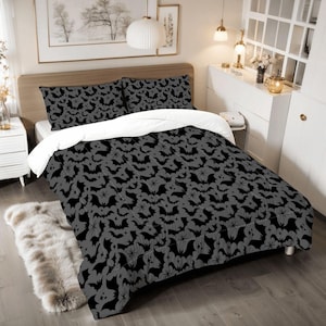 May include: A black and gray comforter with a bat pattern. The comforter is on a bed with white and gray pillows.