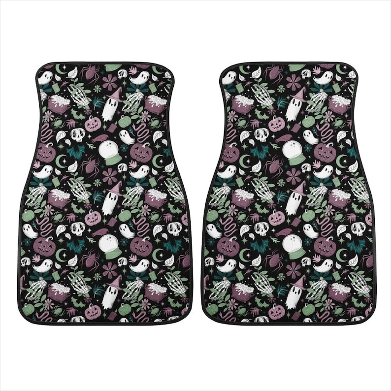 May include: Two black car floor mats with a Halloween themed pattern. The pattern features ghosts, pumpkins, cauldrons, and other spooky elements in shades of green, purple, and white on a black background.