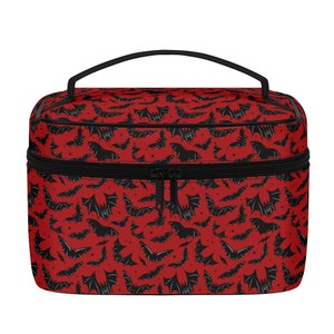 May include: Red travel makeup bag with a black zipper and a black bat pattern.