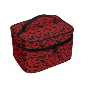 May include: Red and black travel makeup bag with a bat pattern. The bag has a zipper closure and a black handle.