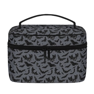 May include: A black and gray travel makeup bag with a zipper closure and a handle. The bag has a repeating pattern of black bats on a gray background.
