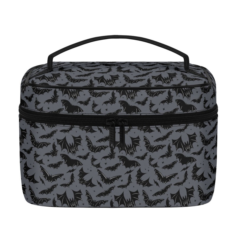May include: A black and gray travel makeup bag with a zipper closure and a handle. The bag has a repeating pattern of black bats on a gray background.