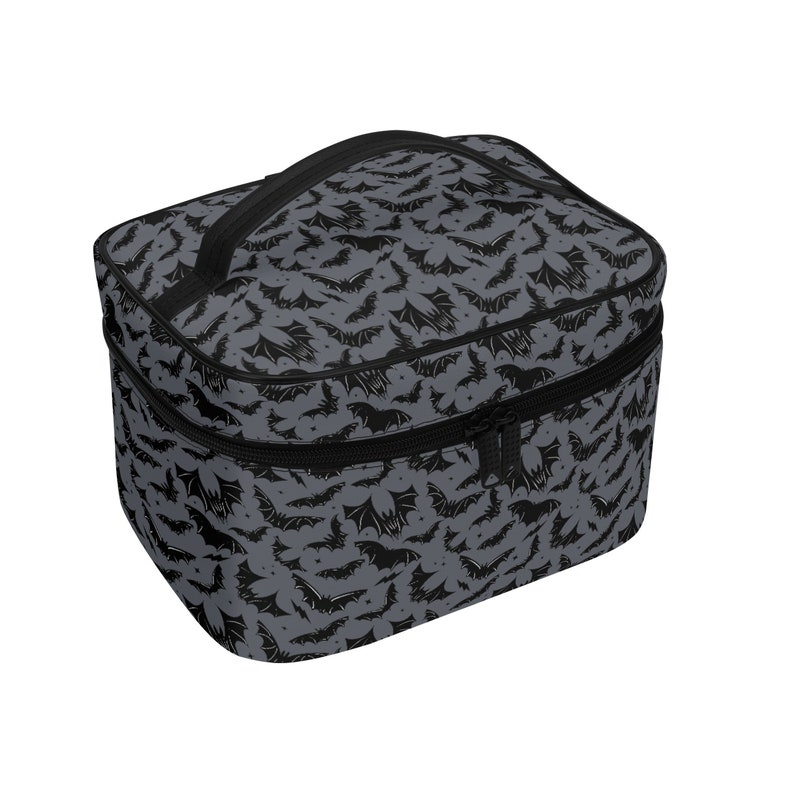 May include: A gray and black travel makeup bag with a zipper closure and a black handle. The bag has a repeating pattern of black bats on a gray background.