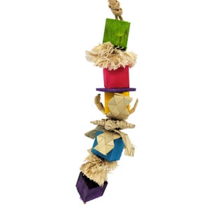 May include: A colorful bird toy with a hanging rope. The toy features stacked wooden blocks in green, red, yellow, blue, and purple, interspersed with natural fiber accents. The toy is designed for birds to play with.