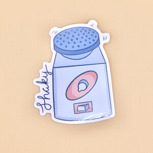 May include: A blue and white sticker with a cartoon illustration of a shaker with the word "shakey" written on the side.