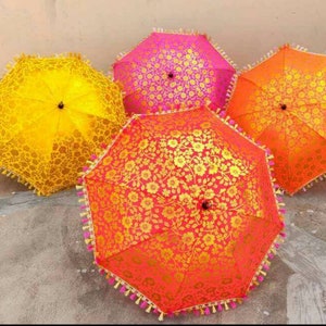 May include: Four colorful umbrellas with floral patterns. The umbrellas are yellow, pink, orange, and red with gold accents. The umbrellas have tassels around the edges.