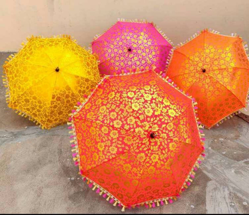May include: Four colorful umbrellas with floral patterns. The umbrellas are yellow, pink, orange, and red with gold accents. The umbrellas have tassels around the edges.