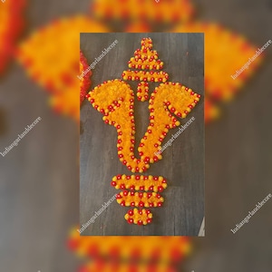 May include: A floral arrangement in the shape of the Hindu deity Ganesha. The arrangement is made of yellow and red marigold flowers.