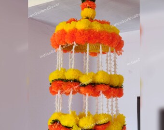 May include: A decorative hanging made of orange and yellow fabric flowers. The flowers are arranged in a circular pattern and are suspended from a white string. The hanging is perfect for adding a touch of color and festivity to any room.