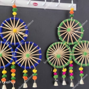 Op de afbeelding: Twee sets van drie decoratieve wandhangers. Elke set heeft drie ronde, geweven strooien frames met blauwe en groene stoffen trim. De frames zijn op elkaar gelegd en hebben kleurrijke pompoenen die eronder hangen.