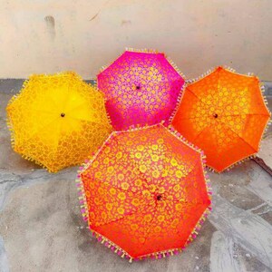 May include: Four decorative umbrellas with floral patterns. Two umbrellas are yellow, one is pink, and one is orange. The umbrellas have tassels around the edges.