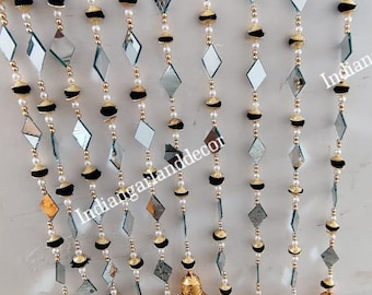 May include: A decorative garland with mirrored diamond shapes, black pom-poms, and gold beads. The garland is finished with small, gold-coloured bells. Ideal for festive decorations, the design is eye-catching.