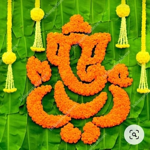 Può includere: Un arrangiamento floreale di calendule a forma della divinità indù Ganesha. L'arrangiamento è su uno sfondo di foglie di banano verdi.