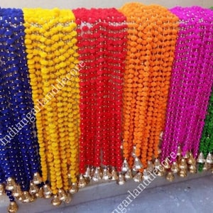 Puede incluir: Un conjunto de guirnaldas de tela de colores con detalles de campanillas. Las guirnaldas están hechas de pompones en azul, amarillo, rojo, naranja, rosa y verde.