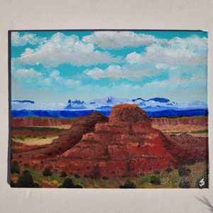 May include: Acrylic painting depicting a desert scene with red rock formations under a blue sky with white clouds. The artwork captures the scale and beauty of the natural environment.