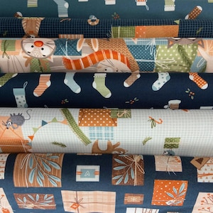 May include: Close-up of several rolls of fabric with various patterns. Designs include gift boxes, socks, and animal illustrations in shades of blue, orange, green, and white. The fabric appears to be cotton or a similar material.