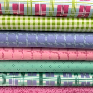 Könnte beinhalten: Ein Stapel bunter Stoffe mit verschiedenen Mustern. Die oberste Schicht zeigt ein rosa-blaues Karomuster. Darunter befinden sich Lagen aus grünem Vichy, lila Karos, rosa Karos, mintgrün mit Rauten und einem Blumenmuster.