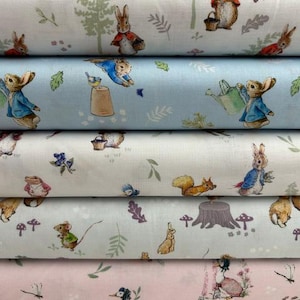 May include: Five stacked bolts of fabric featuring repeating illustrations of rabbits in blue jackets, squirrels, and woodland elements. The patterns are set against white, light blue, and soft pink backgrounds with various forest motifs.