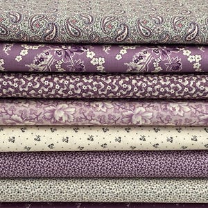 May include: A stack of six purple and white fabric scraps with various floral and paisley patterns.