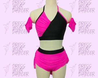 May include: A pink and black dance costume with a halter top and a skirt. The top has a diagonal black panel and a ruffle on one shoulder. The skirt has a black waistband and a ruffled hem.
