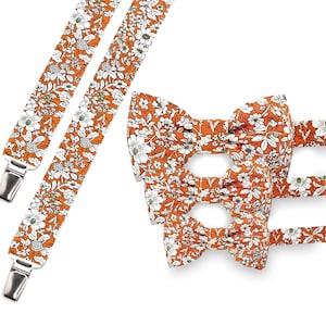 May include: Orange floral suspenders and bow ties. The suspenders have silver metal clips. The bow ties are in three different sizes. The floral pattern includes white flowers and green leaves.