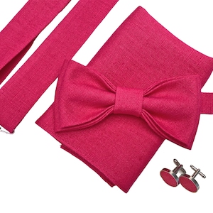 Könnte beinhalten: Ein Set aus rosa Fliege, Hosenträgern und Manschettenknöpfen. Fliege und Hosenträger sind aus strukturiertem Stoff. Die Manschettenknöpfe sind silberfarben.