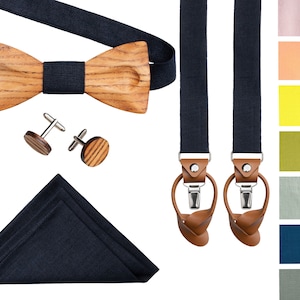 Puede incluir: Un conjunto de accesorios para hombre que incluye una pajarita de madera, gemelos, un pañuelo de bolsillo y tirantes. La pajarita y los gemelos están hechos de madera con un patrón de veta natural. El pañuelo de bolsillo y los tirantes son de color azul marino.